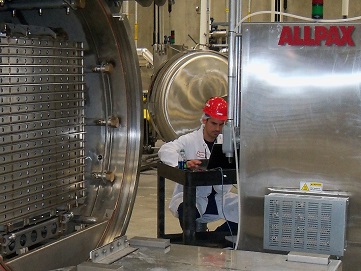 seated man working at Allpax retort processing equipment